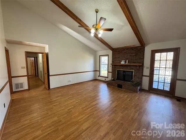 a view of empty room with wooden floor and fireplace