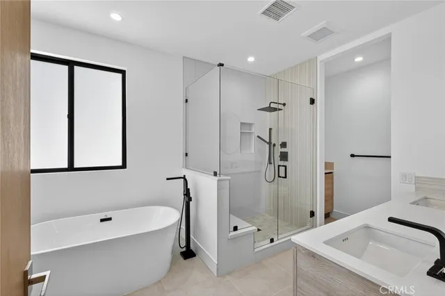 a bathroom with a tub a sink and a large mirror