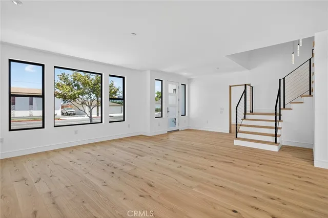 a view of an empty room with wooden floor and windows