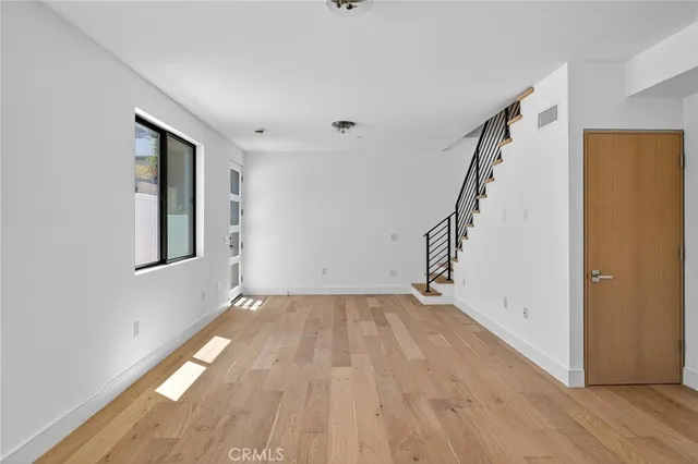a view of an empty room with wooden floor and stairs