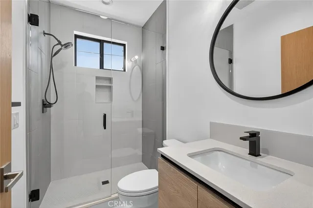 a bathroom with a granite countertop sink a toilet and shower