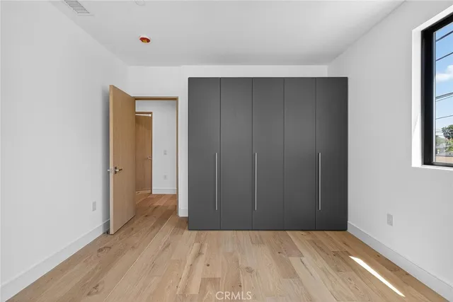 a view of an empty room with wooden floor and closet