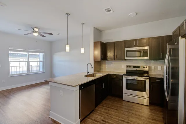 a kitchen with stainless steel appliances granite countertop a stove a sink and a microwave
