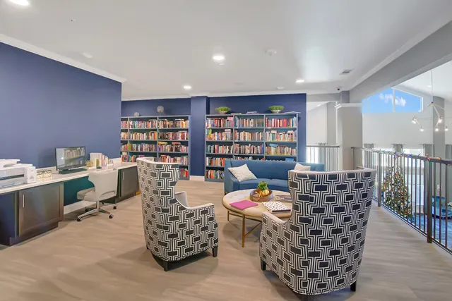 a living room with furniture a bookshelf and a wooden floor