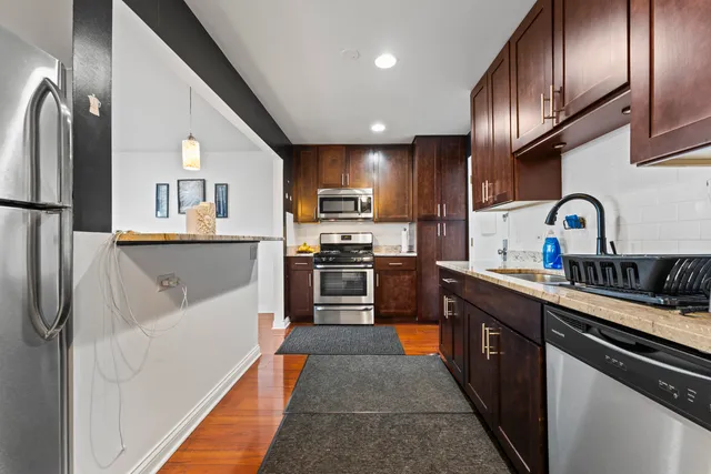 a kitchen with stainless steel appliances granite countertop a refrigerator a sink and a stove