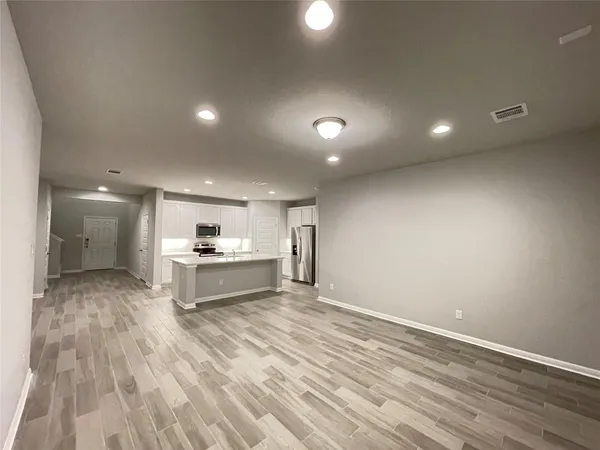 a large white kitchen with kitchen island a sink stainless steel appliances and cabinets