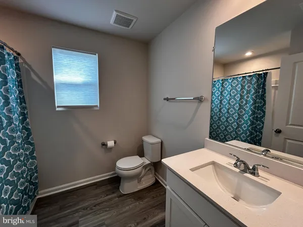a white toilet sitting next to a bathroom sink and a mirror