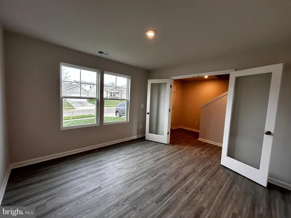 an empty room with wooden floor and windows