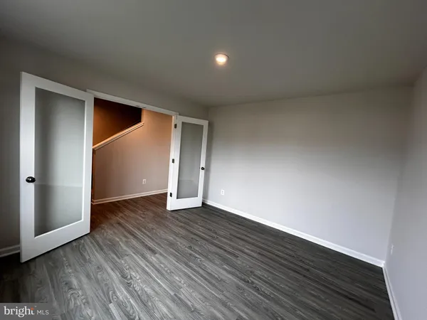 a view of an empty room with wooden floor and closet