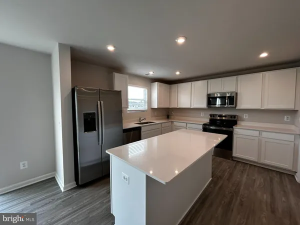 a kitchen with a refrigerator a microwave oven and a sink with wooden floor