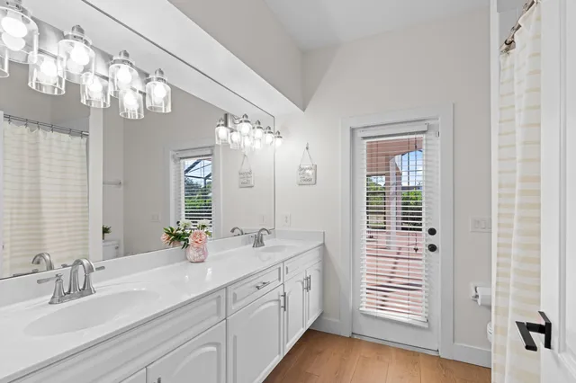 a spacious en suite bathroom with a double vanity sink a large mirror and shower