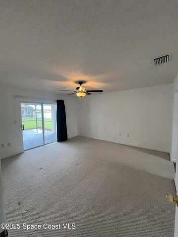 a view of an empty room with a chandelier fan