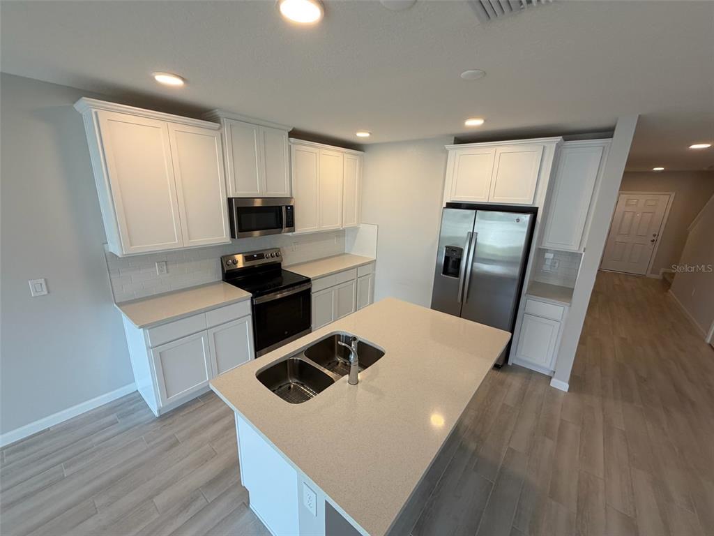 4632 Campsite Loop Orlando, FL 32824 - Photo 3 of 22 a kitchen that has a microwave a stove and white cabinets