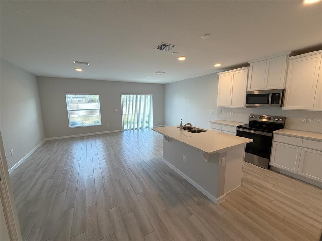 4632 Campsite Loop Orlando, FL 32824 - Photo 4 of 22 a view of kitchen with cabinets wooden floor and black appliances