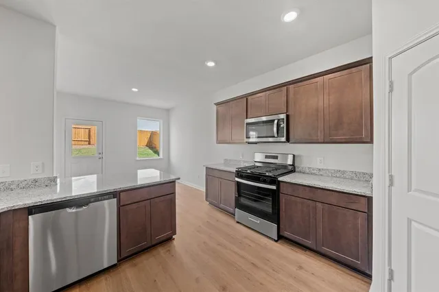 a kitchen with stainless steel appliances granite countertop a stove a sink and a refrigerator