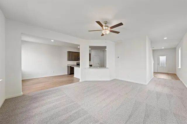 a view of empty room with wooden floor and ceiling fan