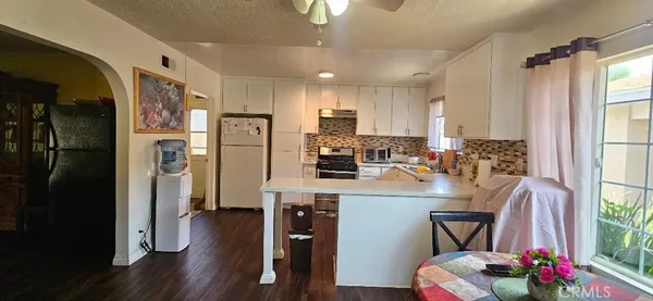 a kitchen with stainless steel appliances granite countertop a refrigerator a stove a sink dishwasher and a dining table with wooden floor
