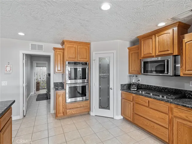 a very nice looking open kitchen with stainless steel appliances granite countertop a stove a refrigerator a sink a dining table and chairs with wooden floor
