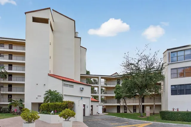a front view of a building with streets and trees