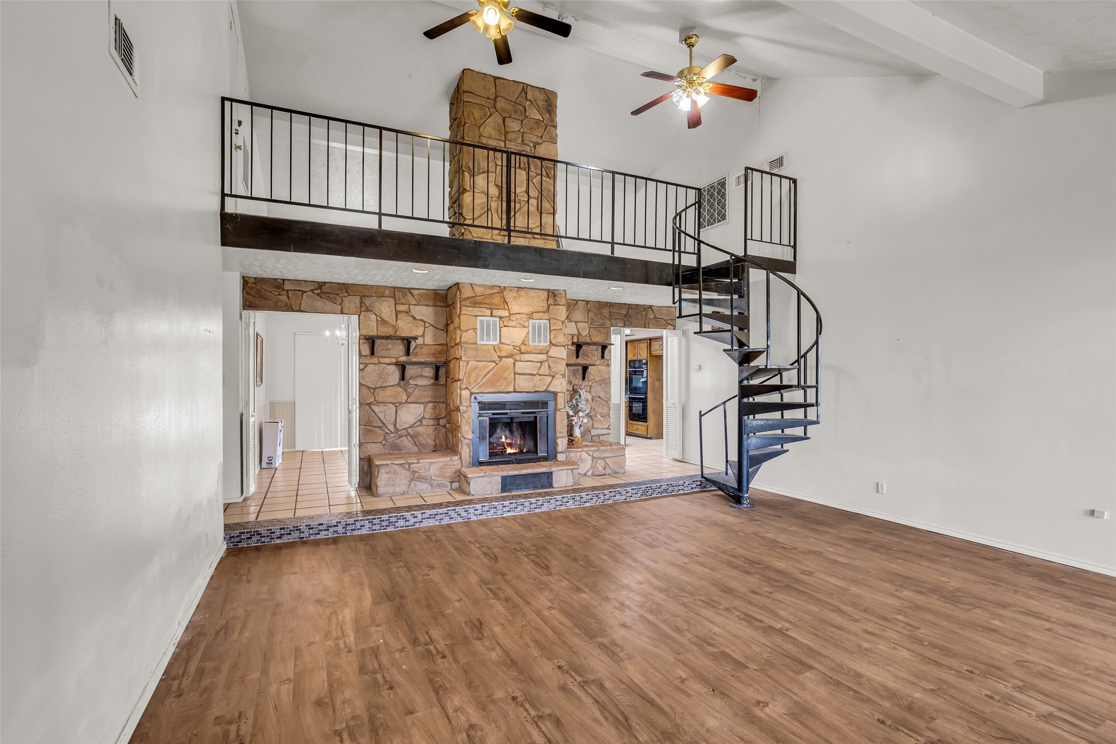 22980 Jade Street Porter, TX 77365 - Photo 4 of 32 an empty room with fireplace wooden floor chandelier fan and windows