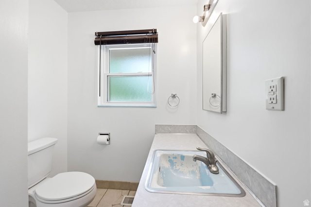 936 Chatelain Road Ogden, UT 84403 - Photo 13 of 33 White walls with a single window, a vanity with a drop-in sink, and a toilet