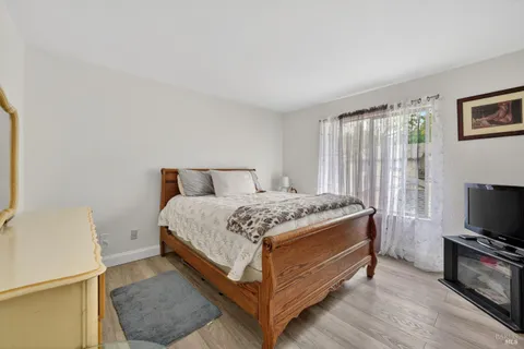 a bed sitting in a spacious bedroom next to a window with pc on the wall