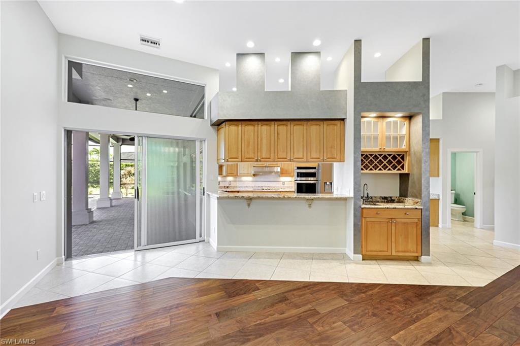 2035 Castle Garden Lane Naples, FL 34110 - Photo 7 of 40 a kitchen with stainless steel appliances granite countertop a refrigerator a sink and a stove