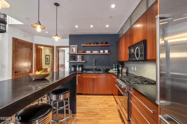 a kitchen with stainless steel appliances granite countertop a sink a stove and a refrigerator