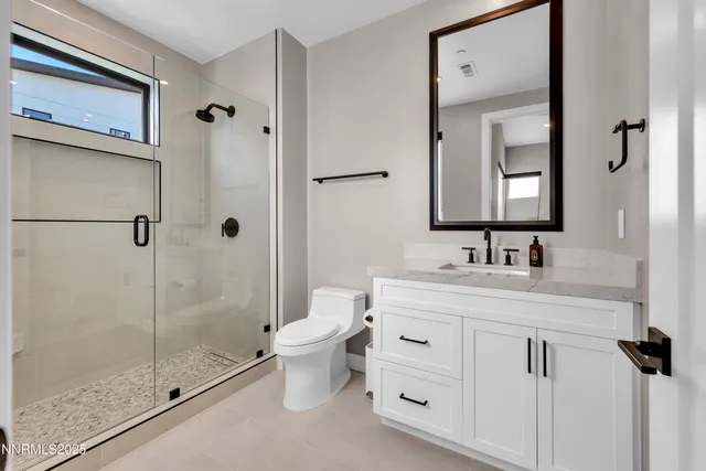a bathroom with a granite countertop sink a toilet and a mirror