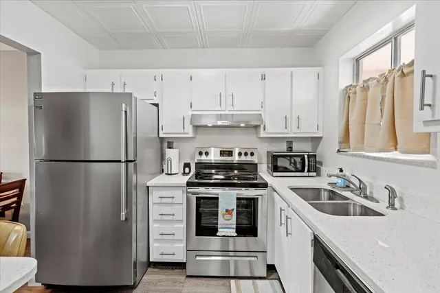 a kitchen with cabinets appliances a sink and a window
