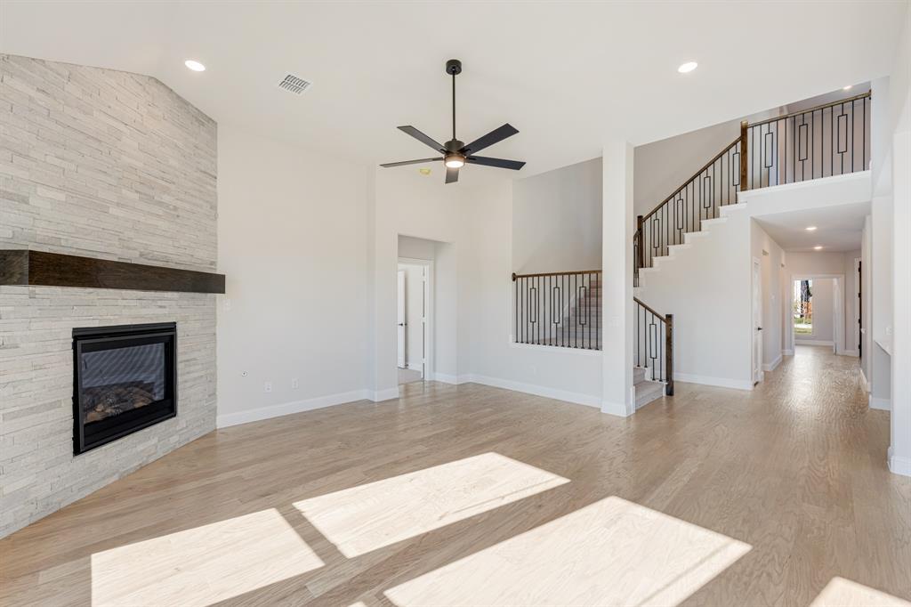 2505 Rileigh Lane Mansfield, TX 76063 - Photo 10 of 40 a view of an empty room with wooden floor fireplace and a kitchen view