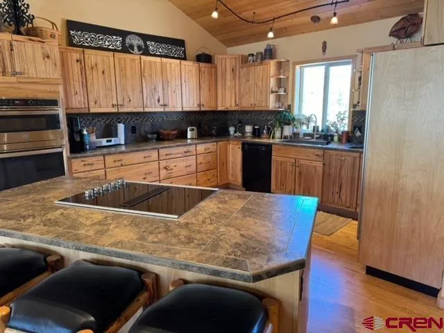 a kitchen with stainless steel appliances granite countertop a sink a stove a counter space and cabinets