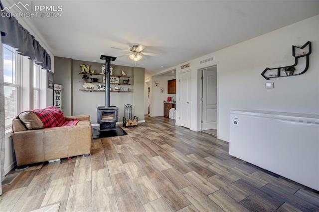 961 Buffalo Run Road Calhan, CO 80808 - Photo 31 of 45 Living room featuring hardwood / wood-style floors, a wood stove, and ceiling fan