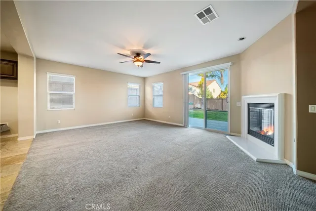 an empty room with chandelier fan and windows
