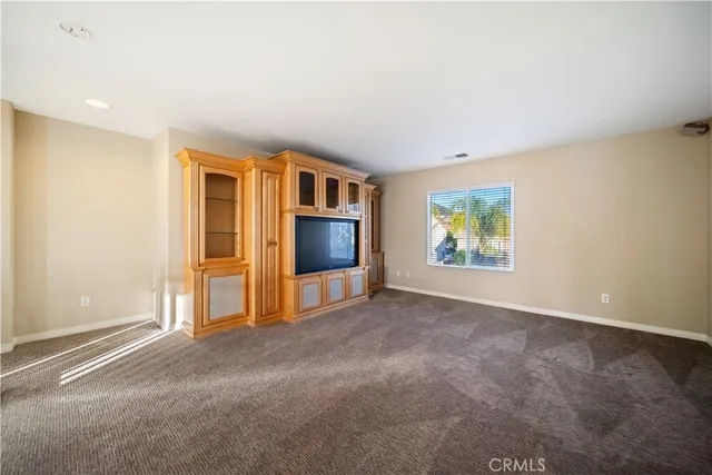 an empty room with a chandelier fan and windows
