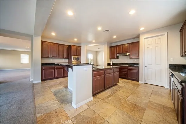 a large kitchen with stainless steel appliances kitchen island granite countertop a large counter top and a stove top oven