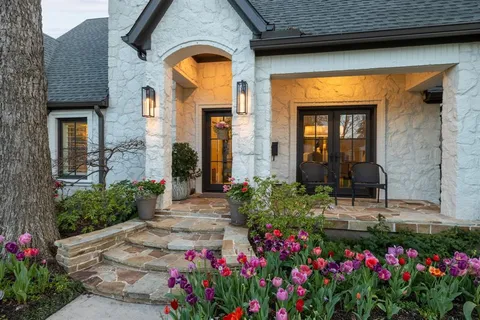 a vase of flowers sitting in front of a brick house