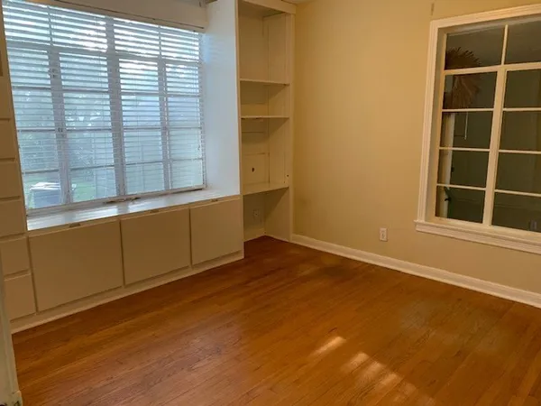 a view of an empty room with a window and wooden floor