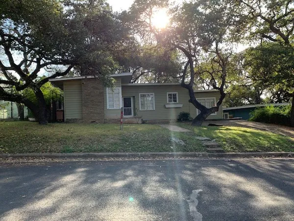 a view of a house with a yard and large tree