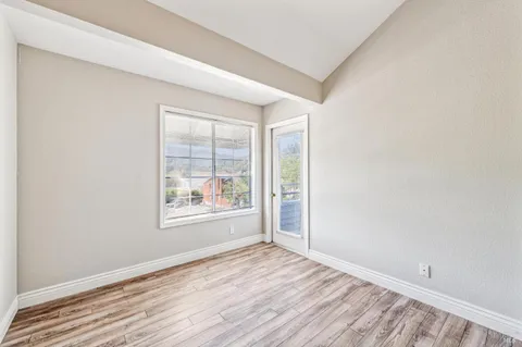 an empty room with wooden floor and windows