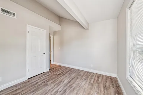 a view of an empty room with wooden floor and a window