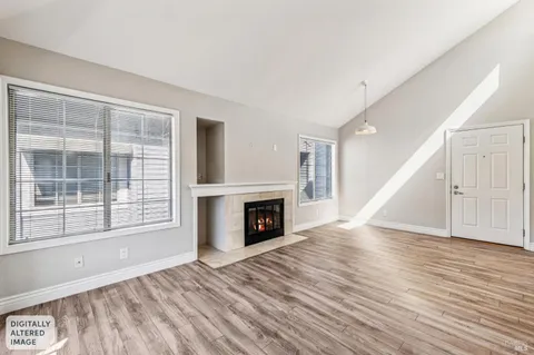 a view of a livingroom with wooden floor a fireplace and windows