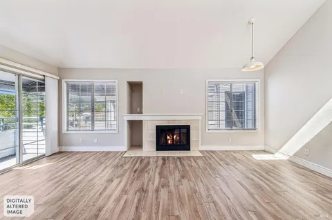 a view of an empty room with wooden floor fireplace and a window