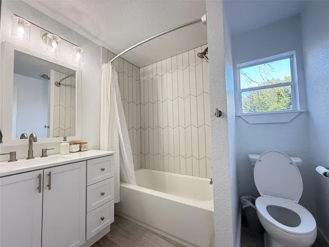 a bathroom with a toilet a sink a bathtub a mirror a vanity and window