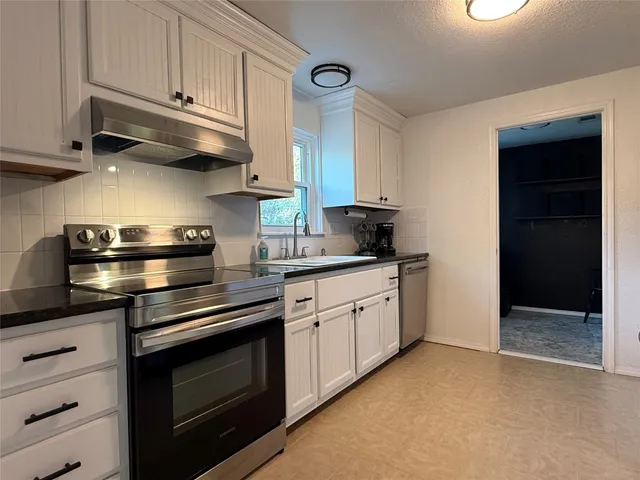 a kitchen with stainless steel appliances granite countertop white cabinets and a stove