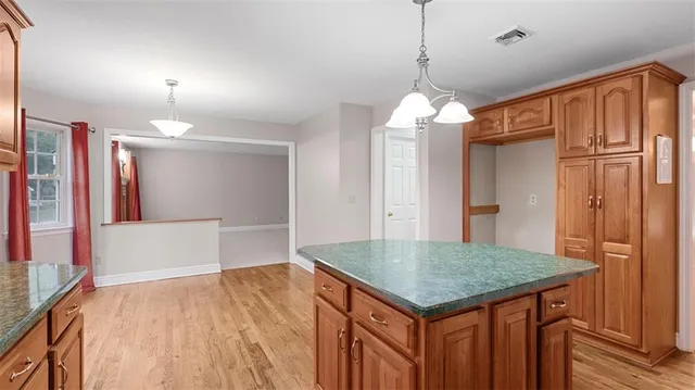a dining room with wooden floor a chandelier a wooden table and chairs