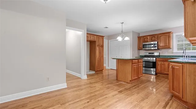 a kitchen with stainless steel appliances granite countertop a refrigerator a sink dishwasher a stove with wooden floor and cabinets