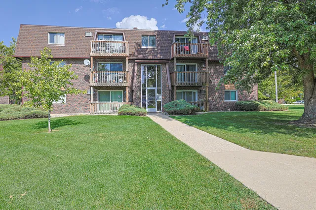 a view of a house next to a big yard and large trees