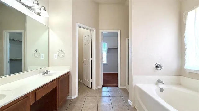 a spacious bathroom with a tub sink shower and mirror