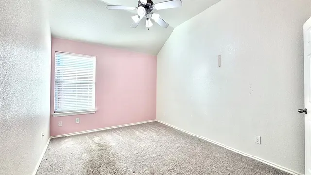 an empty room with a chandelier fan and windows